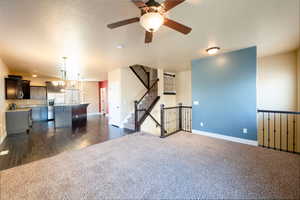 Interior space with ceiling fan with notable chandelier and dark hardwood / wood-style flooring