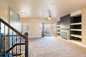 Unfurnished living room featuring a textured ceiling, carpet floors, and ceiling fan