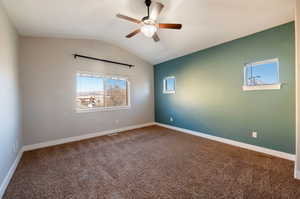 Carpeted empty room featuring vaulted ceiling and ceiling fan