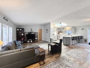 Living room with light wood-type flooring and vaulted ceiling