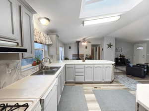 Kitchen with a wood stove, dishwasher, sink, kitchen peninsula, and light wood-type flooring