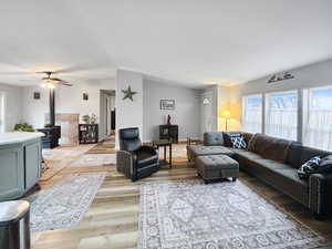 Living room featuring light hardwood / wood-style floors, a wood stove, and ceiling fan