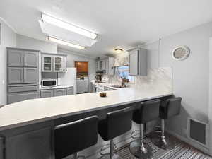 Kitchen featuring a breakfast bar, white appliances, vaulted ceiling, sink, and washer and dryer