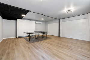 Game room featuring light hardwood / wood-style flooring and an AC wall unit