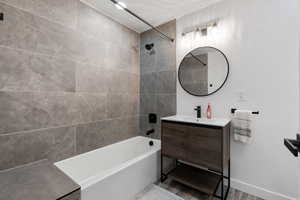 Main bathroom with vanity, tiled shower / bath combo, and laminate wood-style flooring