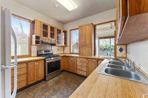 Kitchen featuring white refrigerator, sink, and stainless steel range with gas stovetop