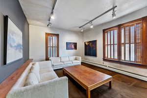 Living room with rail lighting, a textured ceiling, and a baseboard heating unit