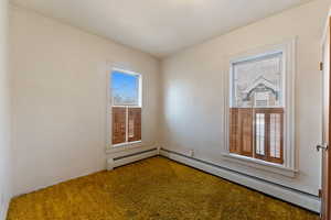 Empty room with carpet and a baseboard heating unit