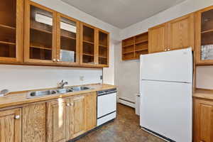 Kitchen featuring baseboard heating, sink, and white appliances