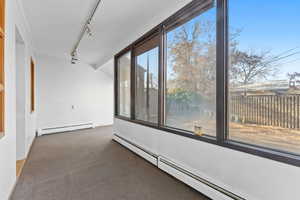 Hallway with carpet floors, rail lighting, and a baseboard heating unit