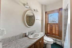 Bathroom featuring baseboard heating, vanity, and toilet