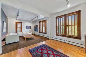 Living room featuring wood-type flooring, rail lighting, and a baseboard radiator