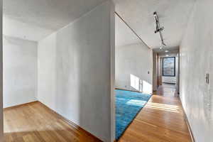 Hallway with track lighting, light hardwood / wood-style flooring, and a baseboard radiator