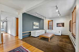 Living room featuring hardwood / wood-style floors, track lighting, and baseboard heating