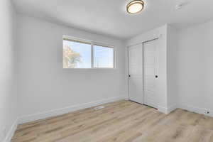 Unfurnished bedroom with a closet, a textured ceiling, and light wood-type flooring