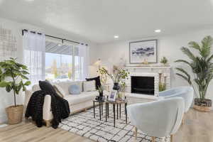 Living room featuring a fireplace, a textured ceiling, and light wood-type flooring