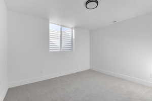 Unfurnished room featuring a textured ceiling and light carpet