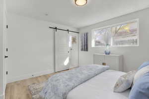 Bedroom with a barn door and light hardwood / wood-style floors