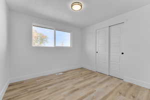 Unfurnished bedroom with a textured ceiling, light hardwood / wood-style floors, and a closet