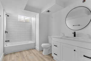 Full bathroom featuring wood-type flooring, vanity, toilet, and tiled shower / bath