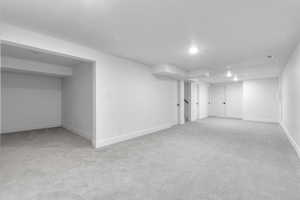 Basement with light colored carpet and a textured ceiling