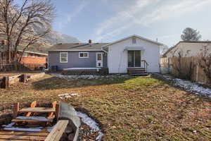 Rear view of house featuring central AC, a mountain view, and a yard