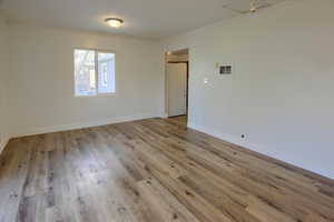 Empty room with light wood-type flooring, ceiling fan, and ornamental molding