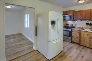 Kitchen featuring tasteful backsplash, sink, stainless steel appliances, and light hardwood / wood-style floors