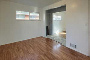 Unfurnished bedroom featuring a closet, wood-type flooring, and multiple windows