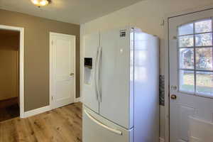 Kitchen featuring white fridge with ice dispenser, light hardwood / wood-style floors, and plenty of natural light