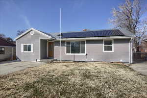 Single story home featuring a front yard and solar panels