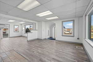 Unfurnished living room with a paneled ceiling and light hardwood / wood-style flooring