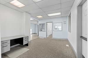 Unfurnished space with a paneled ceiling and light colored carpet