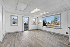 Unfurnished room featuring a drop ceiling, a healthy amount of sunlight, and light wood-type flooring