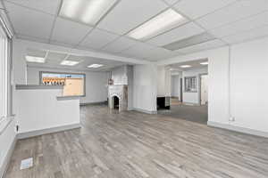 Unfurnished living room featuring a drop ceiling and light wood-type flooring