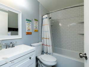 Full bathroom featuring vanity, shower / bathtub combination with curtain, and toilet