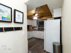 Kitchen featuring white appliances, backsplash, white cabinetry, and sink