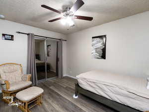 Bedroom featuring ceiling fan, a closet, dark wood-type flooring, and a textured ceiling