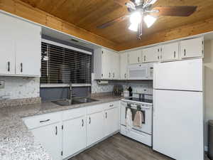 Kitchen featuring white appliances, dark hardwood / wood-style floors, white cabinetry, and sink