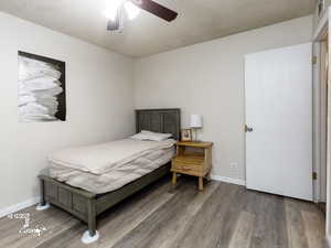 Bedroom with a textured ceiling, hardwood / wood-style flooring, and ceiling fan