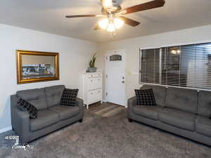 Living room with ceiling fan and dark carpet