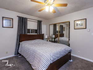 Bedroom with ceiling fan, a closet, a textured ceiling, and dark colored carpet