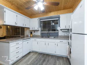 Kitchen with white appliances, sink, light hardwood / wood-style flooring, wooden ceiling, and white cabinets