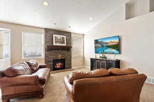 Carpeted living room featuring a textured ceiling, high vaulted ceiling, and a stone fireplace