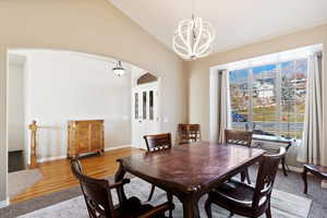 Dining room with a chandelier, wood-type flooring, and lofted ceiling