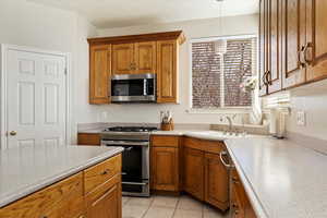 Kitchen featuring light tile patterned flooring, appliances with stainless steel finishes, decorative light fixtures, and sink