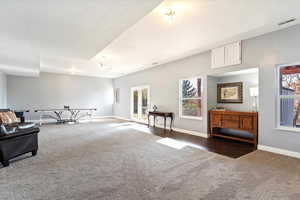 Living area featuring dark colored carpet and a wealth of natural light