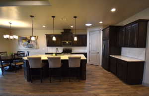 Kitchen with dark brown cabinets, dark hardwood / wood-style flooring, stainless steel appliances, and a kitchen island with sink