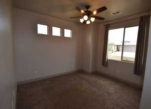 Carpeted empty room featuring ceiling fan