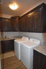 Washroom featuring washer and dryer, sink, cabinets, and dark hardwood / wood-style floors